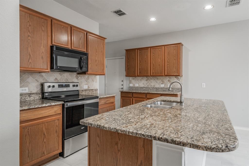 5446 Prairie Lane Grand Prairie, TX 75052 - Photo 11 of 39 a kitchen with granite countertop wooden cabinets and a stove top oven
