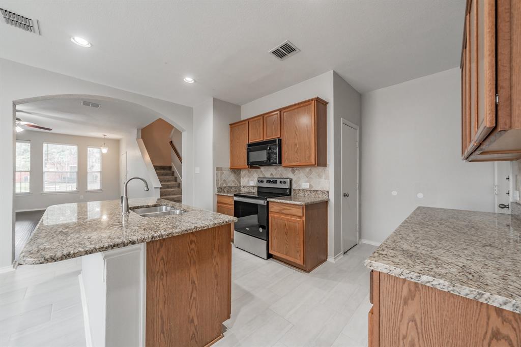 5446 Prairie Lane Grand Prairie, TX 75052 - Photo 12 of 39 a kitchen with granite countertop stainless steel appliances a stove sink and microwave