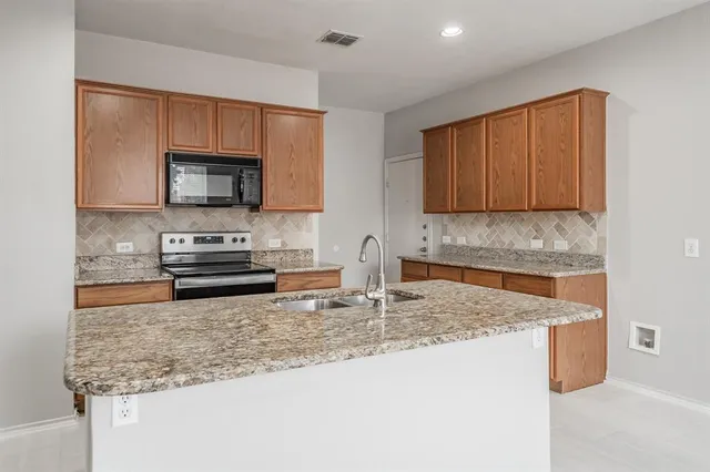 a kitchen with stainless steel appliances kitchen island granite countertop a stove and a sink