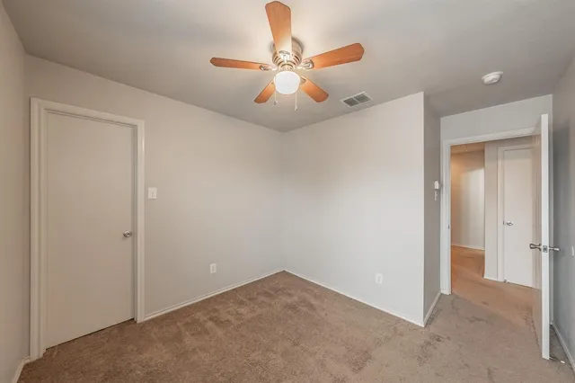an empty room with closet and a chandelier fan