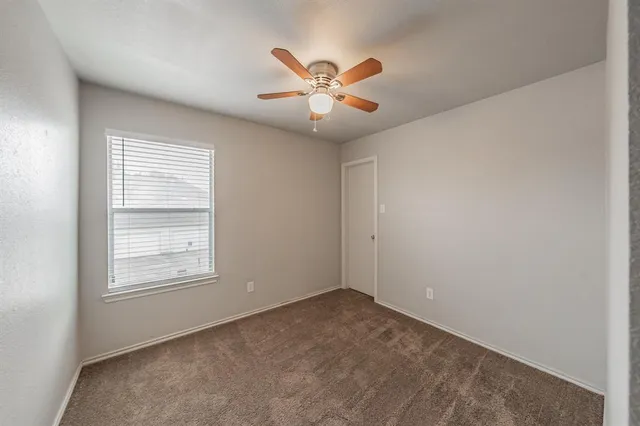 an empty room with a window and a fan