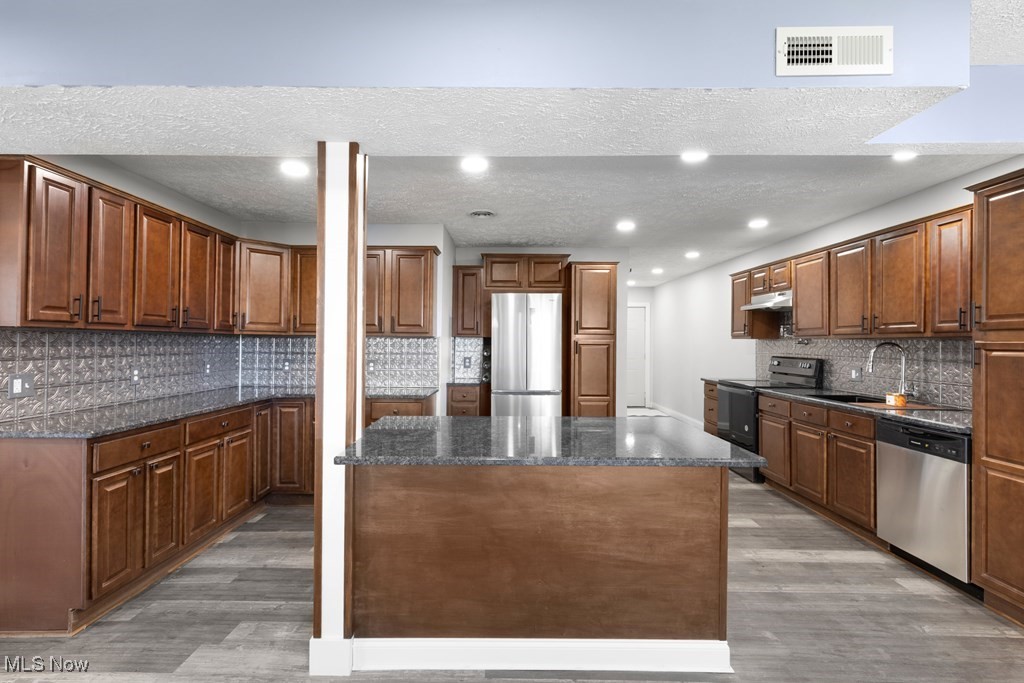 139 Patterson Road Weirton, WV 26062 - Photo 11 of 46 Kitchen featuring decorative backsplash, a textured ceiling, light wood finished floors, appliances with stainless steel finishes, and a kitchen island
