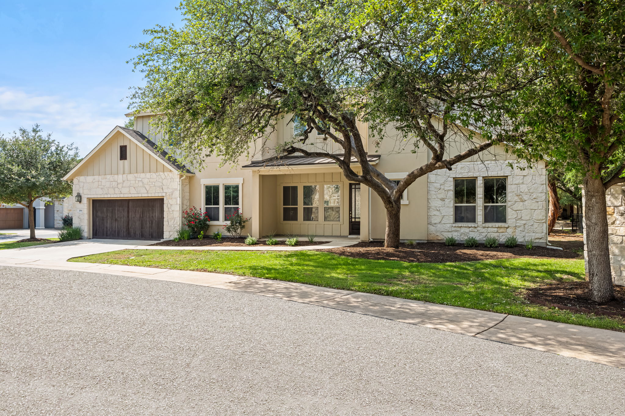 2516 Hopsack Mills Road Austin, TX 78748 - Photo 37 of 39 Stone and stucco exterior with board and batten accents, featuring a two-car garage with wood-finish doors and a covered entry