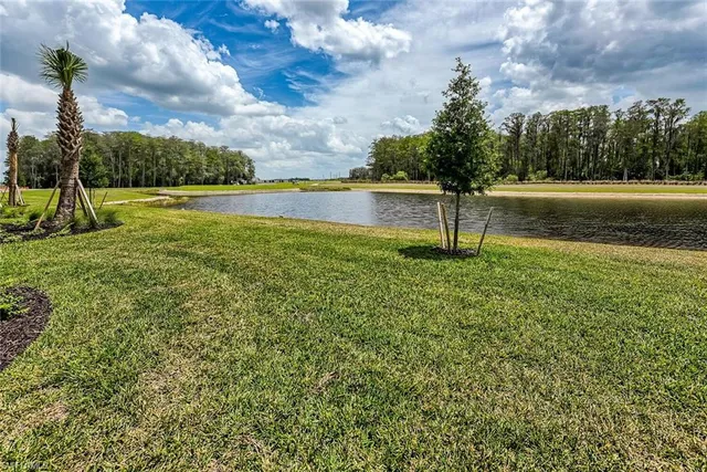 a view of a white house with a big yard and potted plants