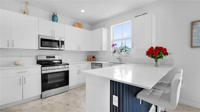 a kitchen with granite countertop kitchen island white cabinets and stainless steel appliances