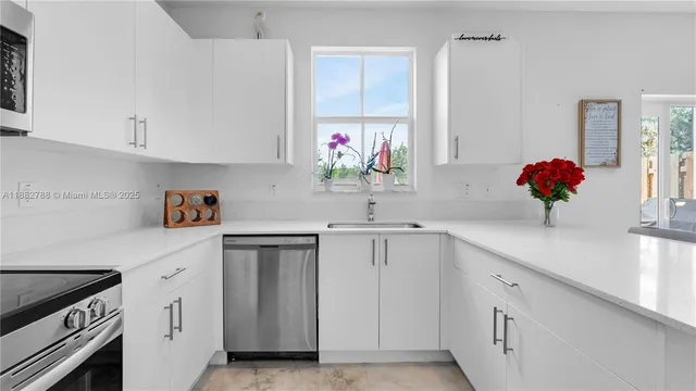 a kitchen with white cabinets and sink