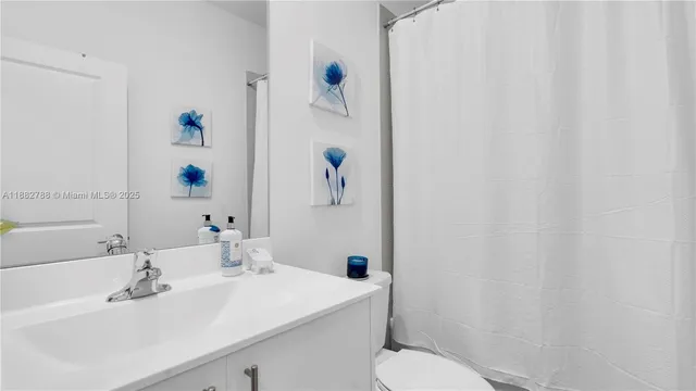 a bathroom with a sink a toilet and shower curtain