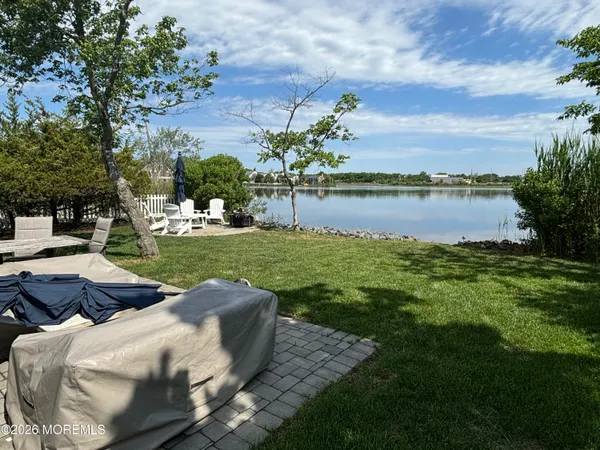 a view of a lake with lawn chairs and a big yard