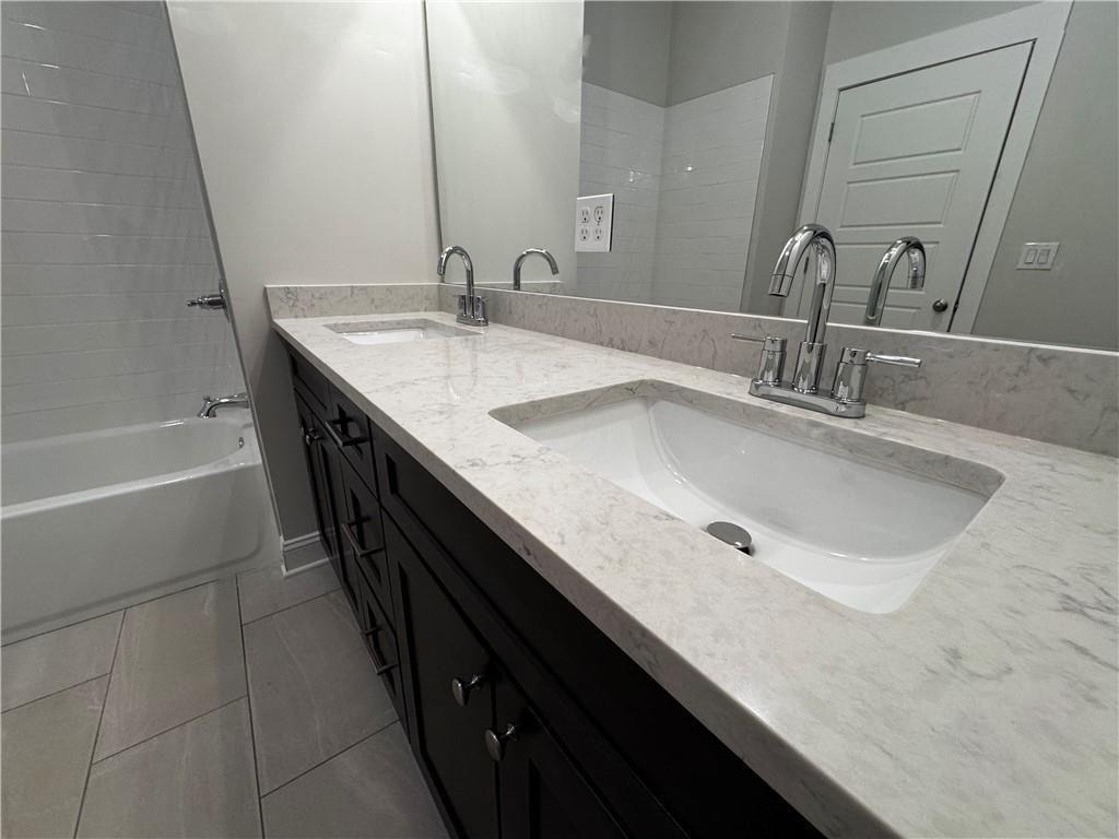 1777 Temple Avenue, Unit P Atlanta, GA 30337 - Photo 21 of 22 a bathroom with a double vanity sink a mirror and a bathtub