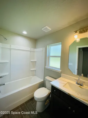 a bathroom with a granite countertop sink toilet a mirror and bathtub