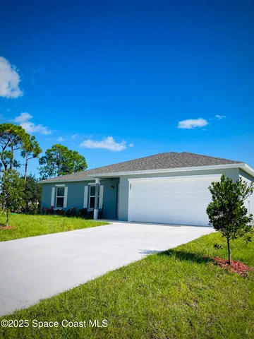 a view of an house with backyard and a tree