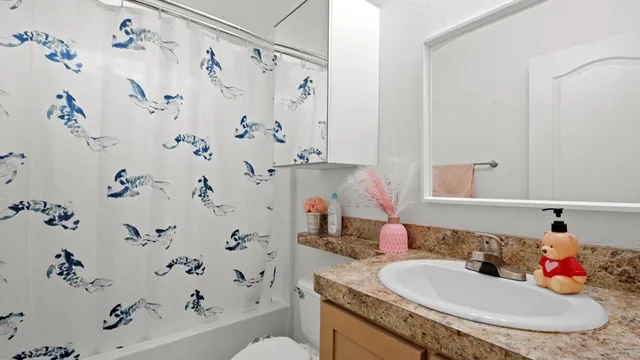 a bathroom with a granite countertop sink a toilet and a shower curtain