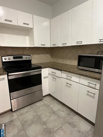 a kitchen with granite countertop a sink a stove and cabinets