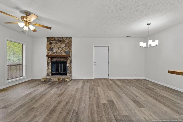 an empty room with wooden floor chandelier and fireplace