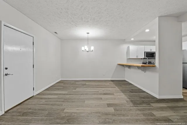 an empty room with wooden floor and kitchen view