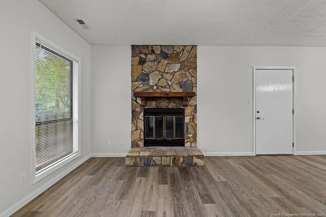 an empty room with wooden floor a fireplace and windows