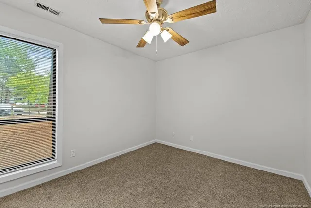 an empty room with a window and a fan