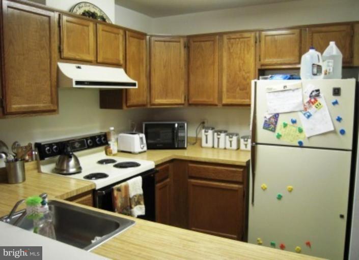 7808 Harrowgate Circle, Unit C Springfield, VA 22152 - Photo 4 of 12 a kitchen with a refrigerator a stove a sink and dishwasher with wooden floor