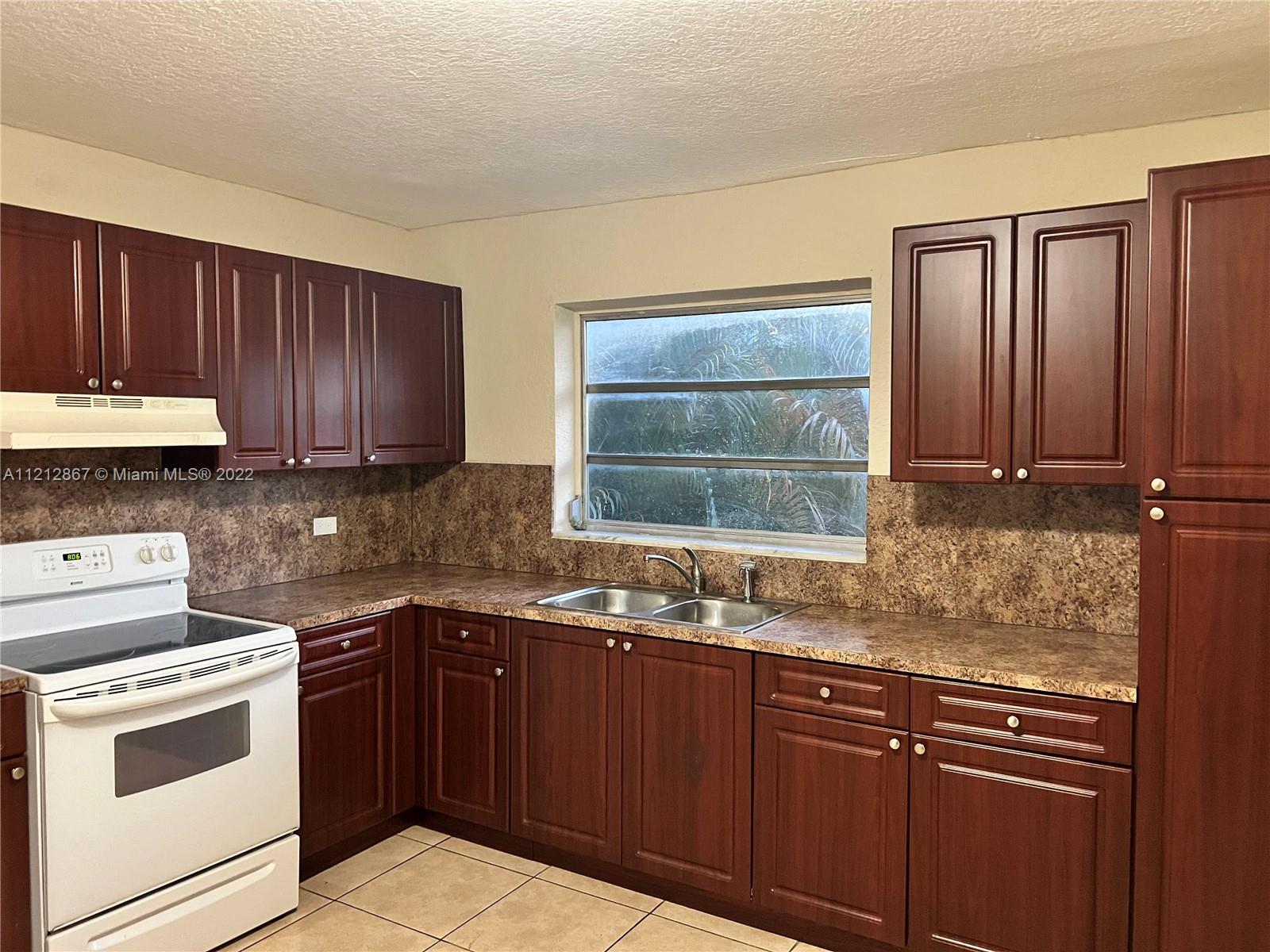 a kitchen with granite countertop wooden cabinets a sink and dishwasher