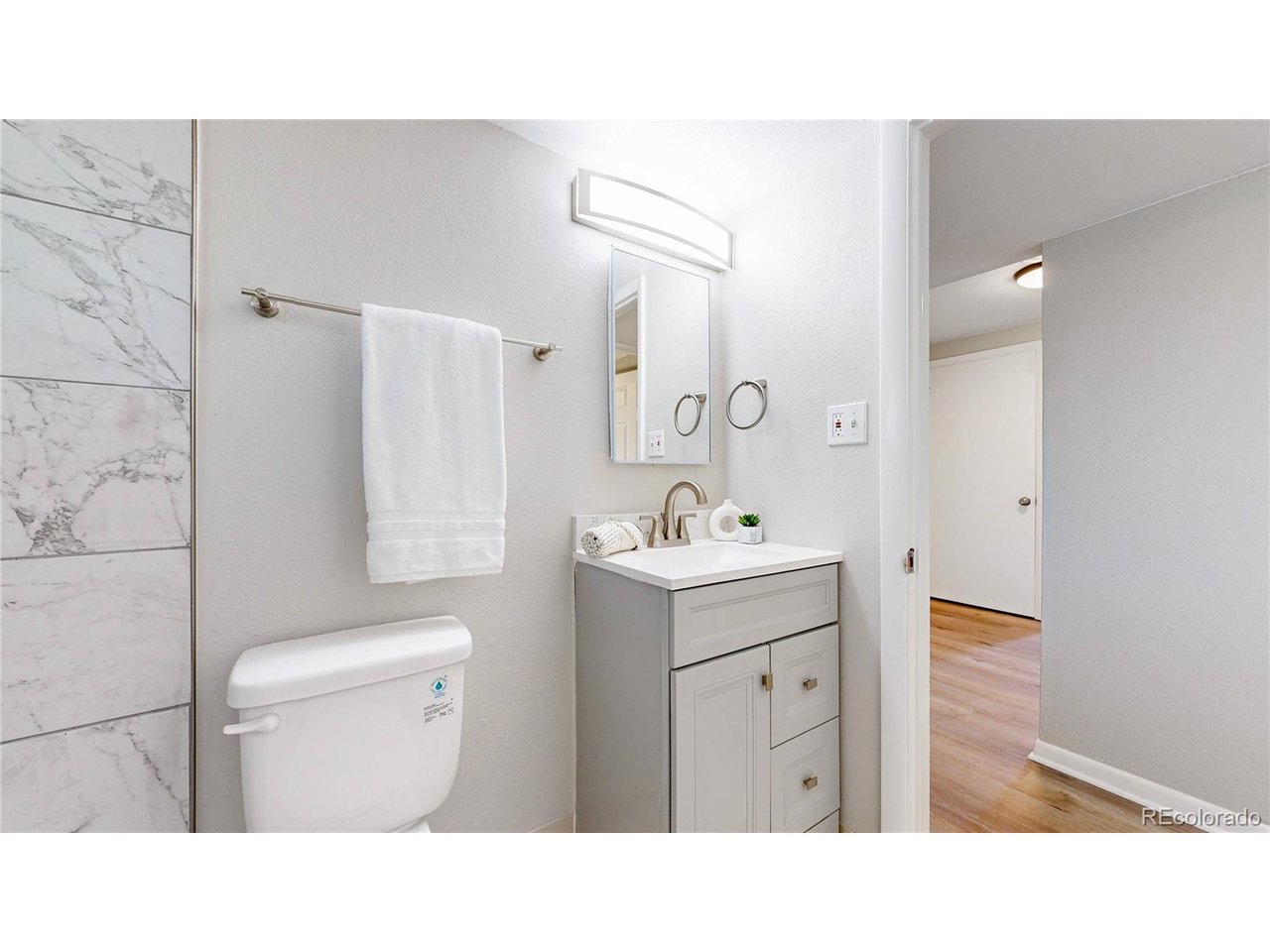 9395 West 45th Avenue Wheat Ridge, CO 80033 - Photo 32 of 48 a bathroom with a sink toilet a mirror and vanity