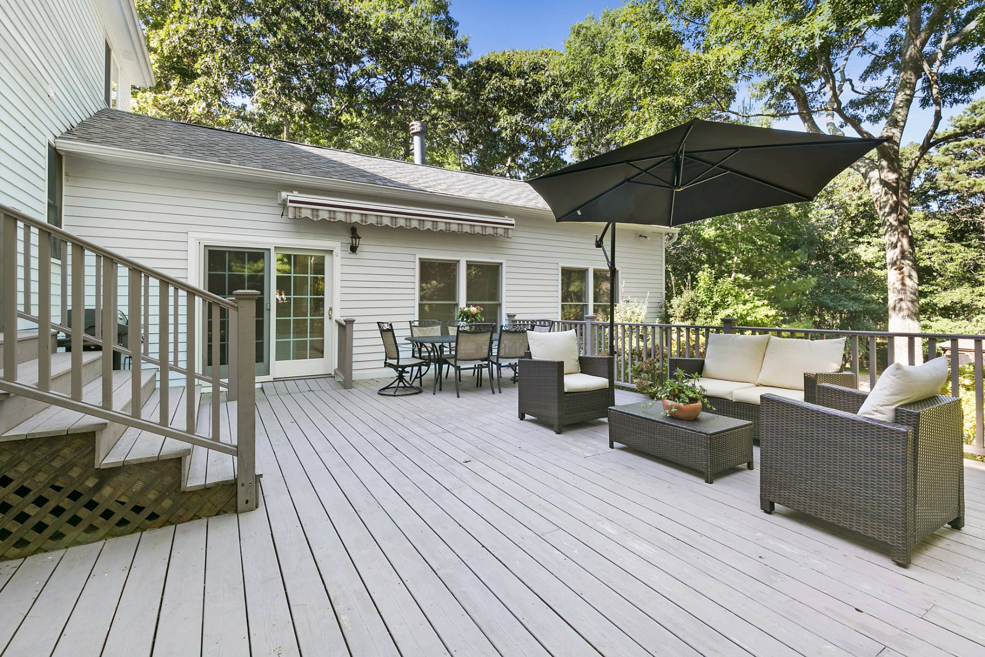 18 Whooping Hollow Road East Hampton, NY 11937 - Photo 13 of 15 a view of a deck with couches table and chairs under an umbrella with wooden floor
