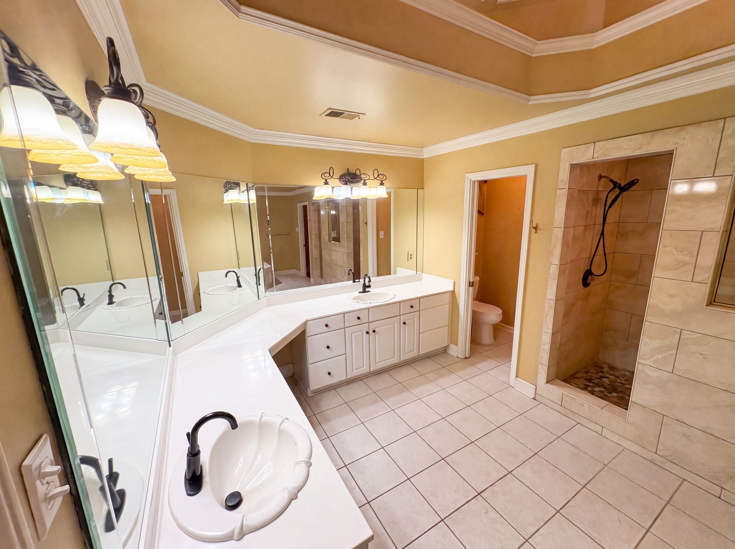 9424 Gotten Road Germantown, TN 38139 - Photo 21 of 27 Bathroom featuring a walk-in shower with stone tile, a dual vanity with white countertops, and white cabinetry