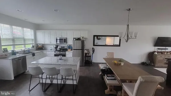 a kitchen with kitchen island a dining table chairs and a wooden floor