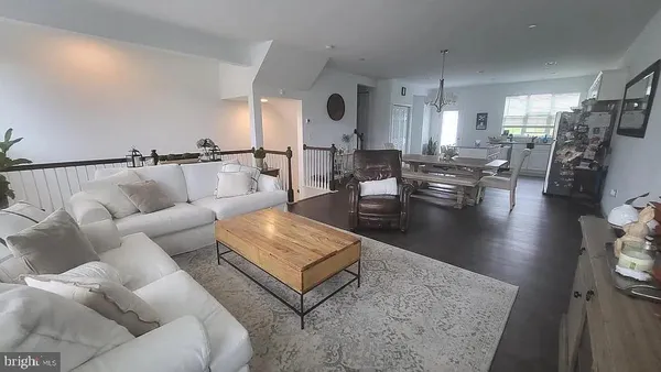 a living room with couches and kitchen view with wooden floor