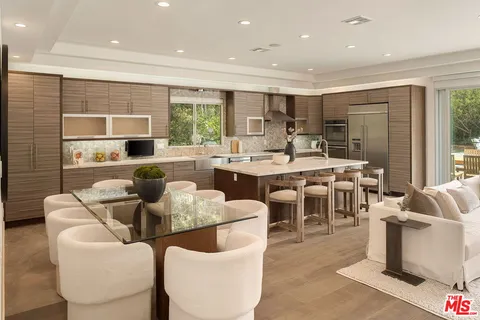 a large kitchen with stainless steel appliances a large counter top a stove a chimney a sink and a large window
