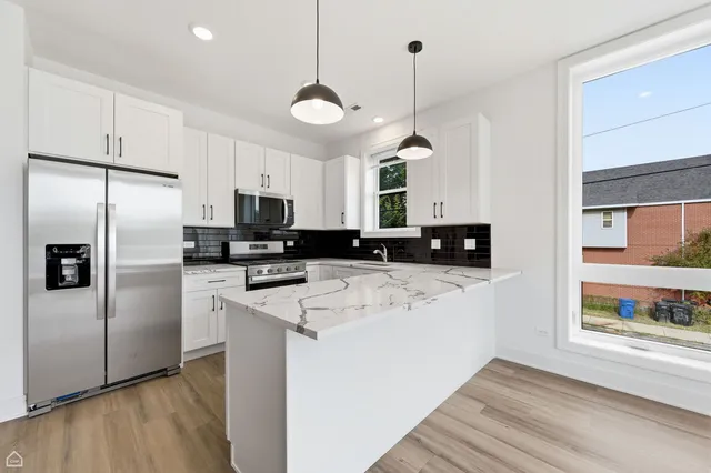 a kitchen with stainless steel appliances granite countertop a refrigerator a sink dishwasher a stove and white cabinets with wooden floor