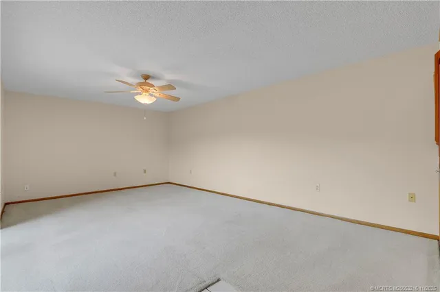 an empty room with a chandelier fan and windows