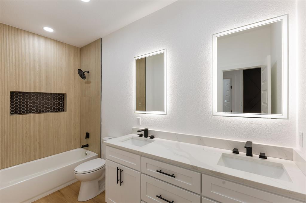 3526 Spring Avenue Dallas, TX 75210 - Photo 20 of 27 Full bathroom featuring a textured wall, double vanity, shower combination, and light wood-style flooring