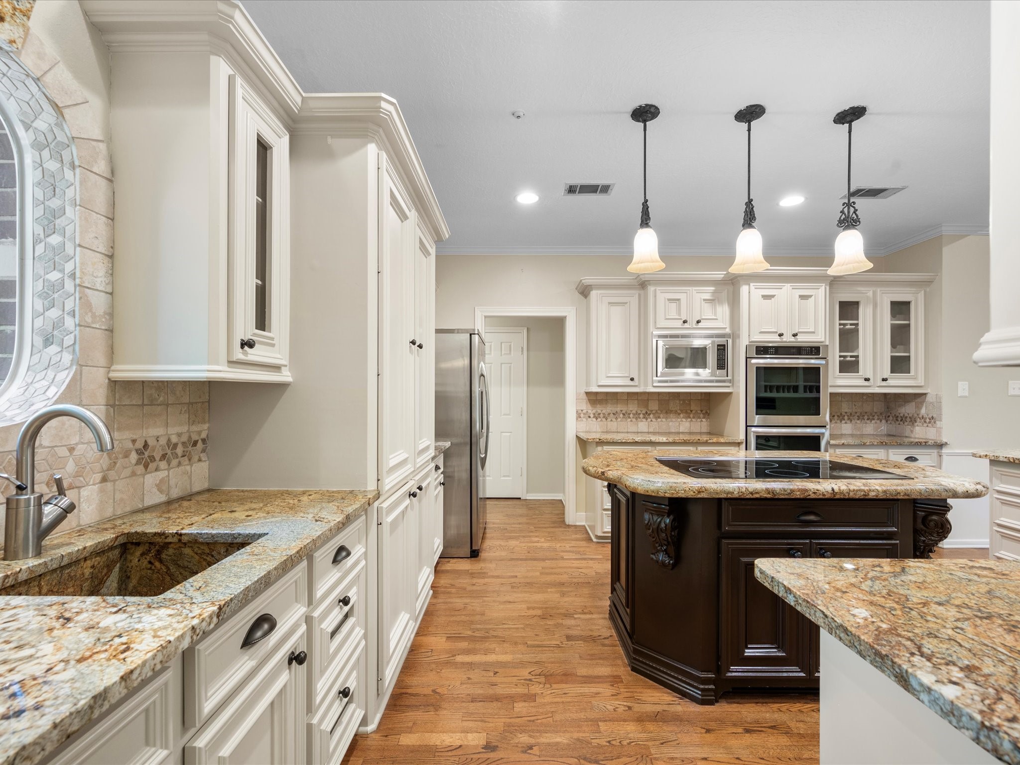 7 Wellesley Drive Conroe, TX 77304 - Photo 5 of 34 a kitchen with stainless steel appliances granite countertop a sink a stove and a wooden floors