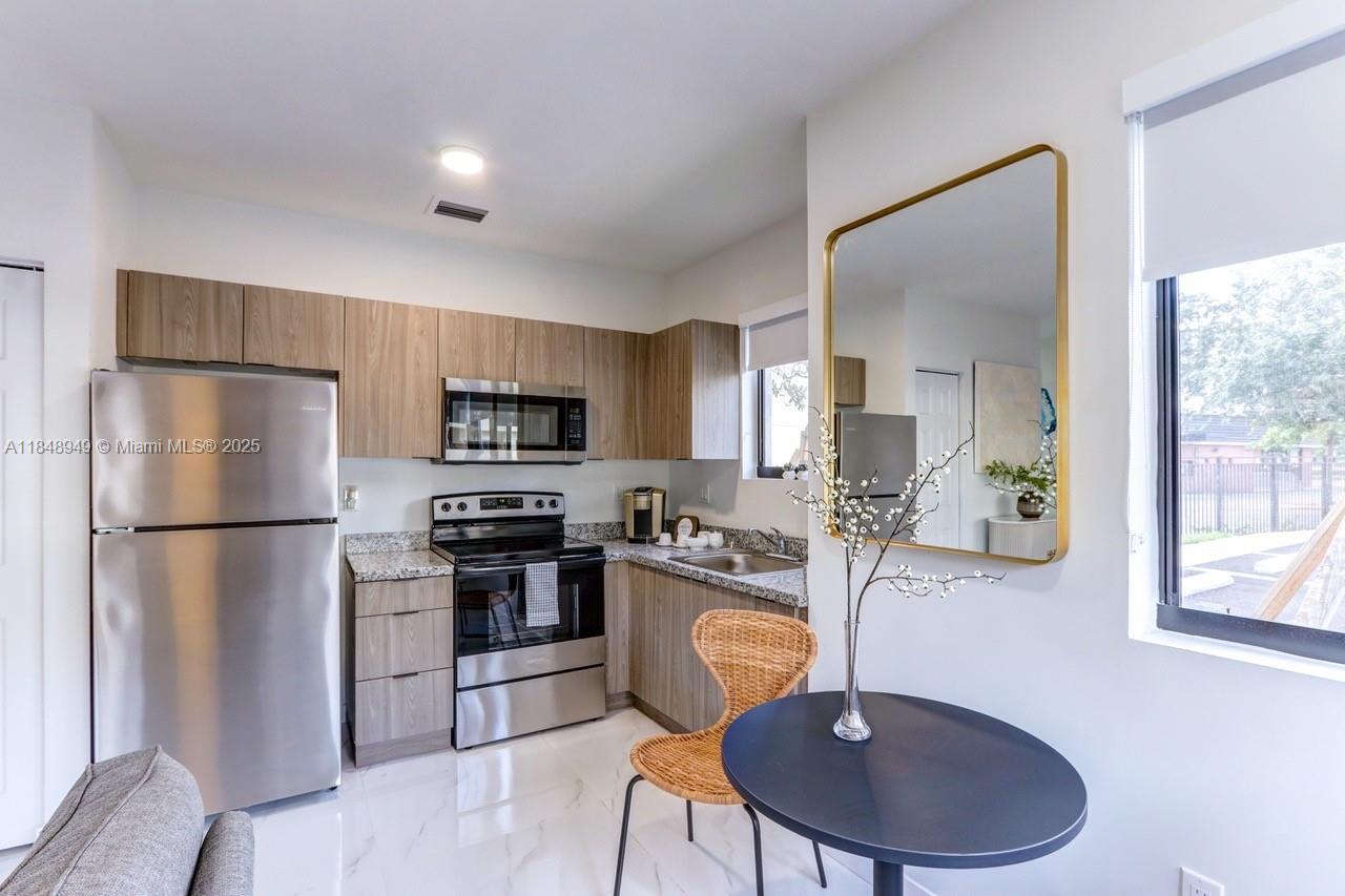 339 West 78th Road, Unit 203 Hialeah, FL 33014 - Photo 3 of 23 a kitchen with stainless steel appliances granite countertop a refrigerator a stove a sink dishwasher a dining table and chairs with wooden floor