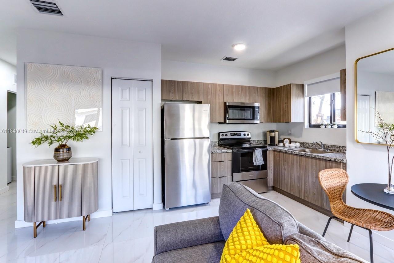 339 West 78th Road, Unit 203 Hialeah, FL 33014 - Photo 5 of 23 a kitchen with granite countertop stainless steel appliances a refrigerator a stove a dining table and chairs