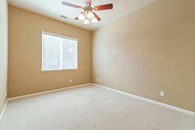 an empty room with a window and a fan