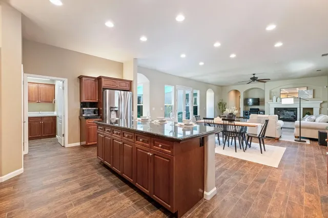 a living room with stainless steel appliances granite countertop furniture wooden floor and a kitchen view