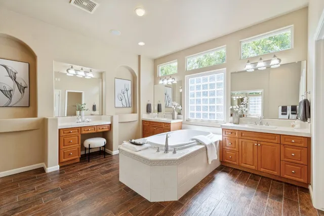 a living room with stainless steel appliances granite countertop a white cabinets a sink and a wooden floor