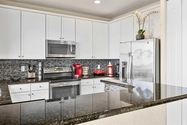 a kitchen with stainless steel appliances granite countertop a stove a refrigerator and a microwave