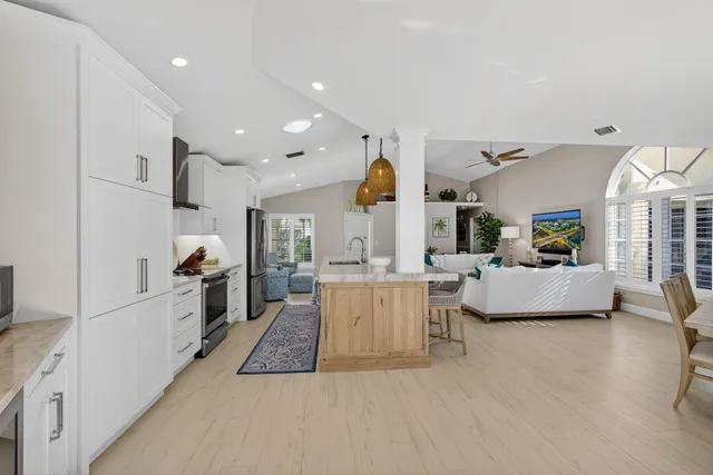 a large white kitchen with lots of counter space a sink and a large window