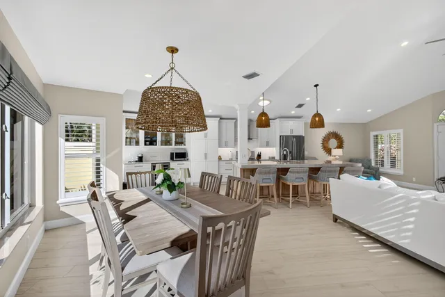 a living room with lots of white furniture a chandelier and a window