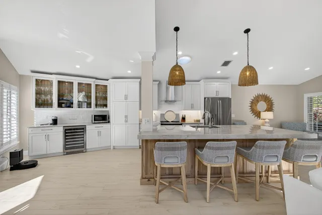 a kitchen with stainless steel appliances a sink a stove and chairs