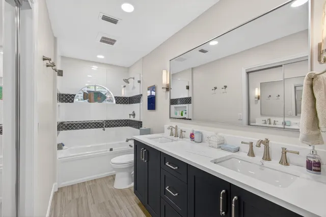 a spacious bathroom with a double vanity sink toilet mirror and shower