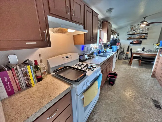 a view of a kitchen with stainless steel appliances a stove a chimney a dining table and chairs