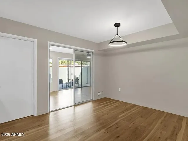 a view of empty room with wooden floor and fan