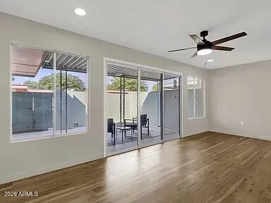 a view of an empty room with window and wooden floor