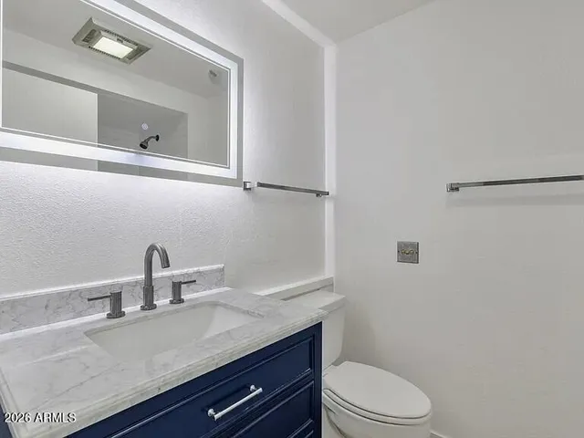 a bathroom with a granite countertop toilet sink and mirror