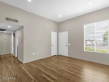 a view of an empty room with wooden floor and a window