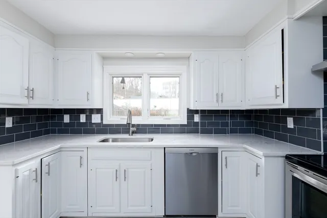 a kitchen with granite countertop white cabinets and sink