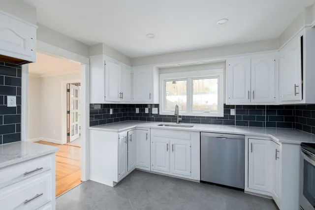 a kitchen with white cabinets sink and dishwasher